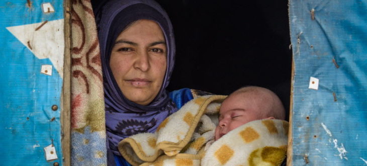 シリアから難民としてレバノンへ逃れ仮住まいのテントで生後2カ月の赤ん坊を抱く母親