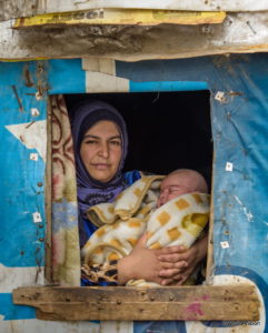 シリアから難民としてレバノンへ逃れ仮住まいのテントで生後2カ月の赤ん坊を抱く母親